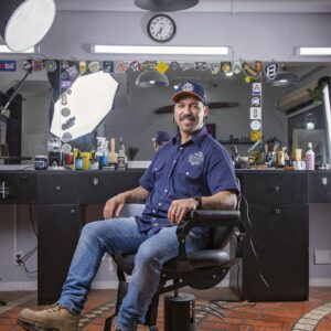 Smiling Barber Sitting on Armchair in Hair Salon