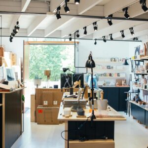 Young ethnic female employee standing at counter in creative gift shop